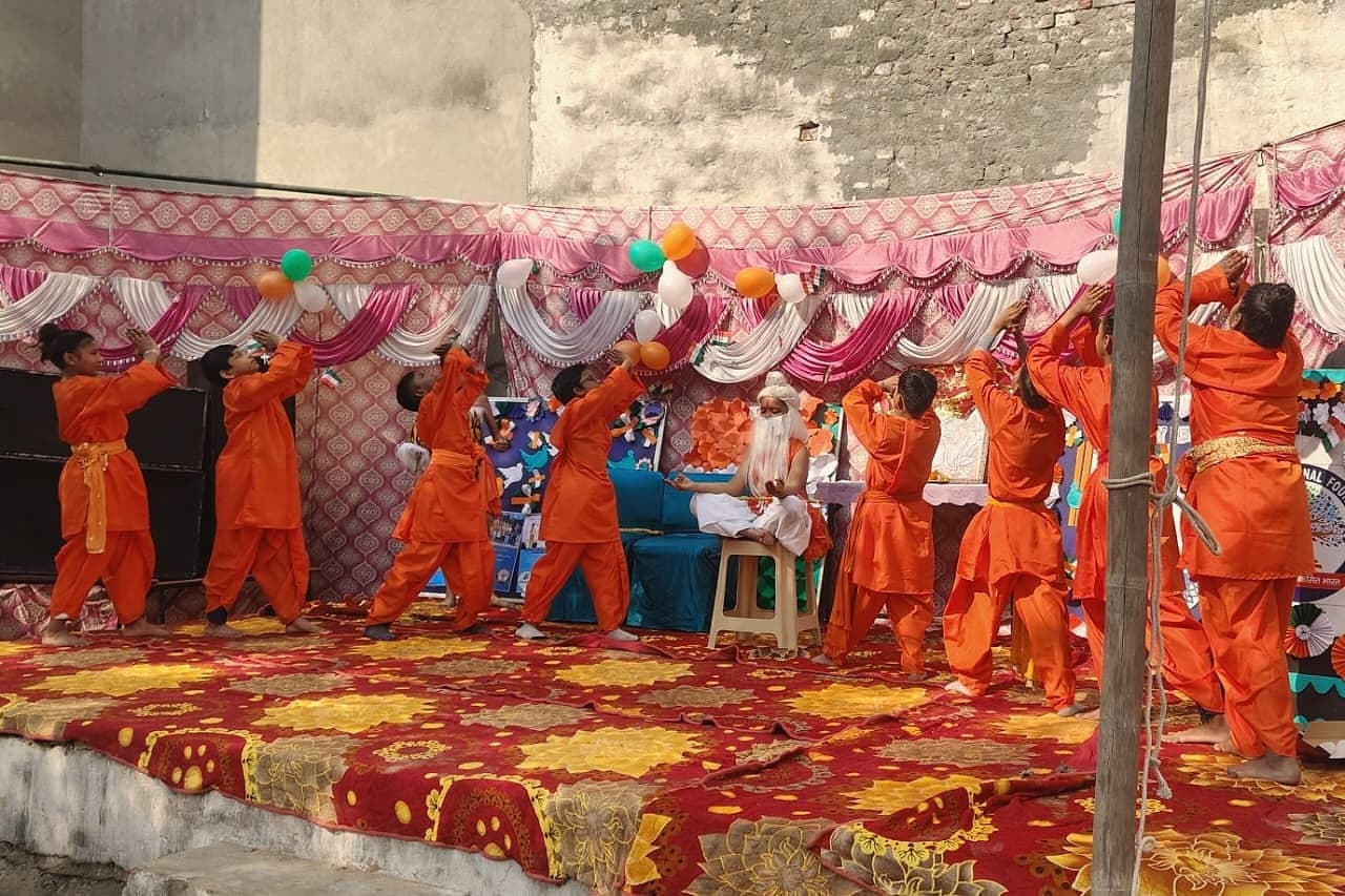 Students performing a group dance in orange costumes at the annual function