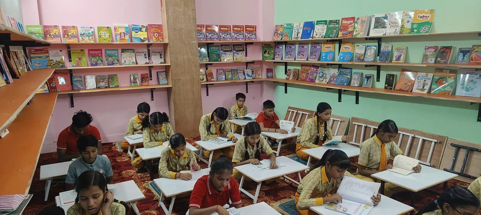 Students working at low desks in the centre library, shelves of books behind them