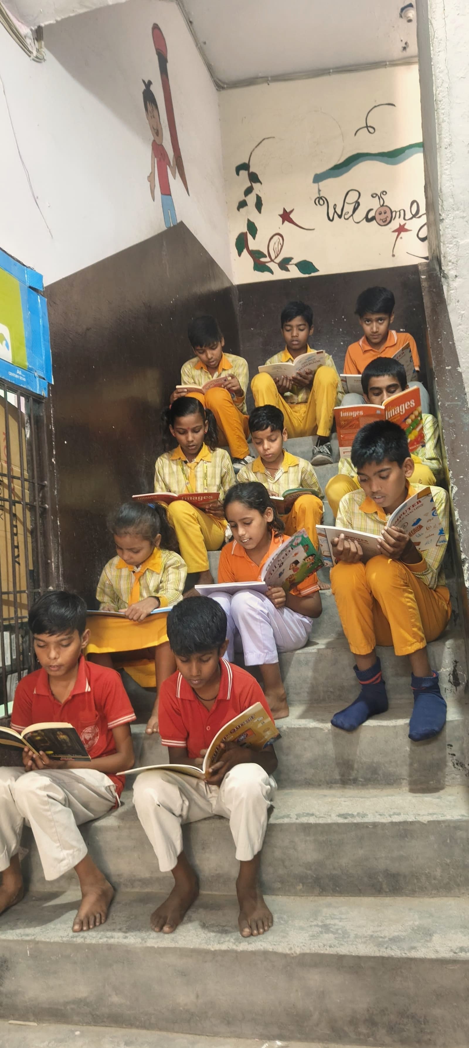 Children sitting together on the floor of the Salarpur learning centre, reading picture books