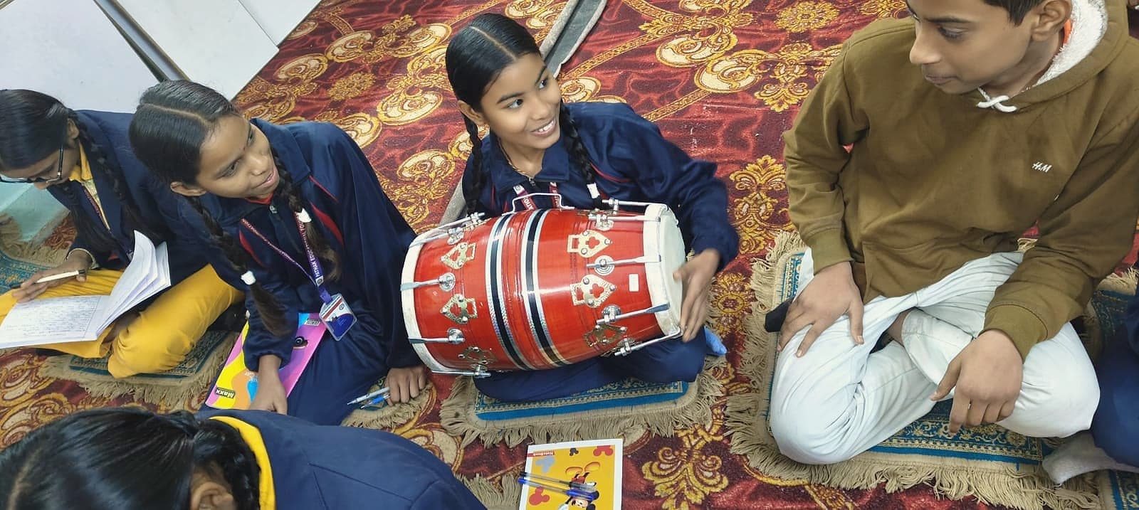 A student playing the dhol during an annual day rehearsal
